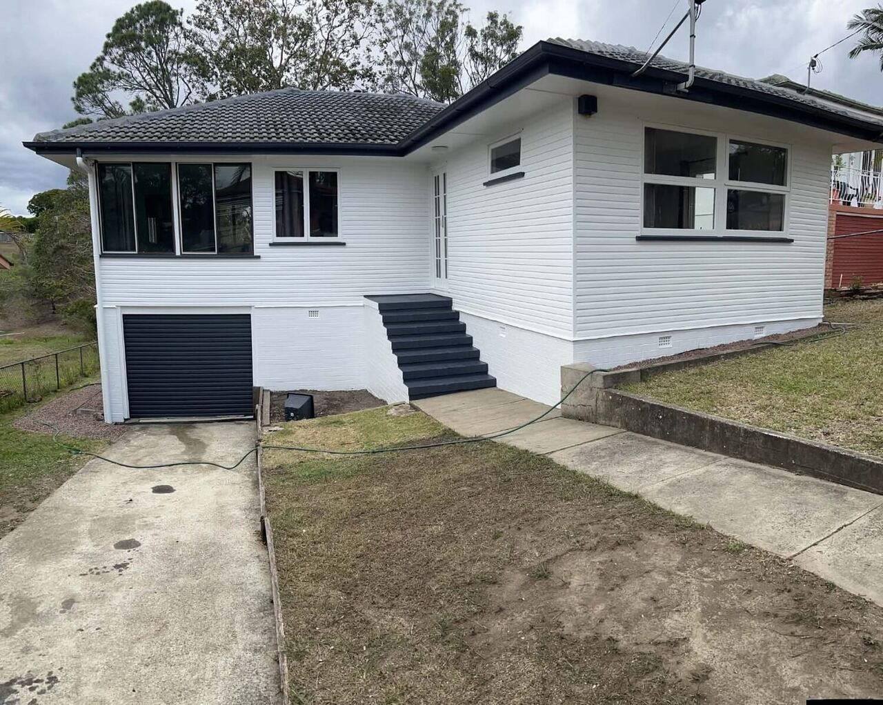 Repainted Brisbane home with a dark roof and crisp white exterior